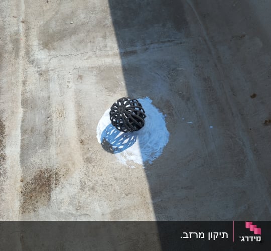 ניקוז עם חומר איטום לבן סביבו על רצפה אפורה